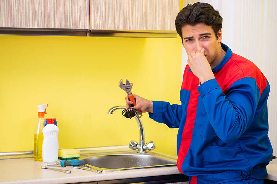 Professional plumber holding nose due to foul smell coming from a clogged drain in Springfield, IL. Expert drain cleaning services.