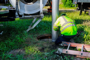 Professional septic tank cleaning specialist using a commercial septic pump to drain sewage from a residential property in Springfield, IL.