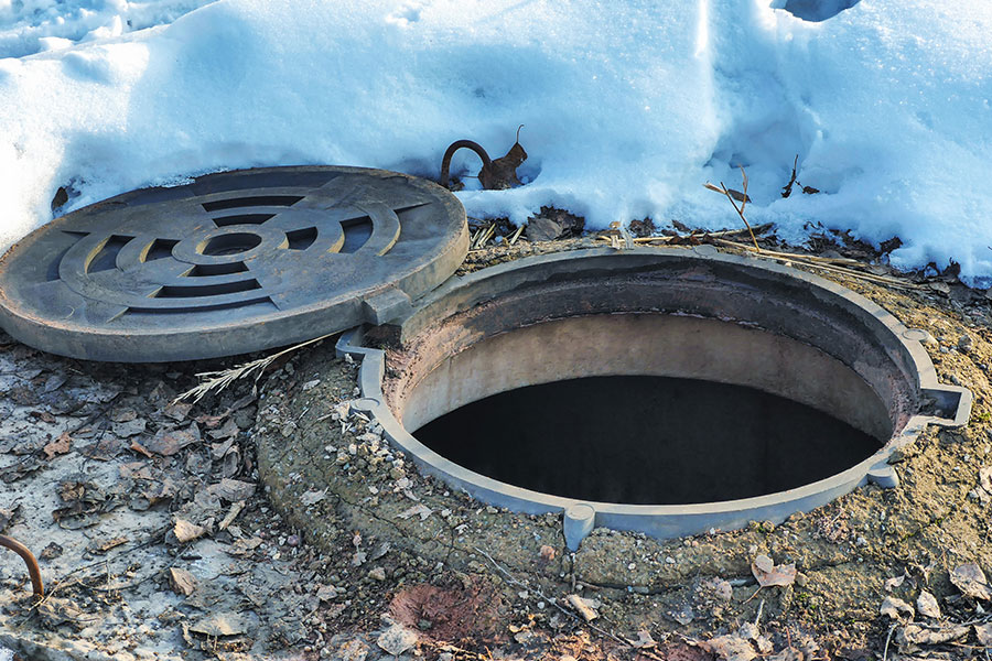 A septic tank manhole at a residential property in Springfield, IL that needs to be pumped with winter snow on the ground.