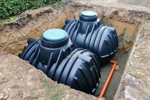 Two black plastic septic tanks being installed on a residential property in Decatur, IL.