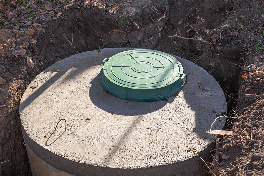 A concrete septic tank with a green plastic cover installed on a residential property in Decatur, IL.