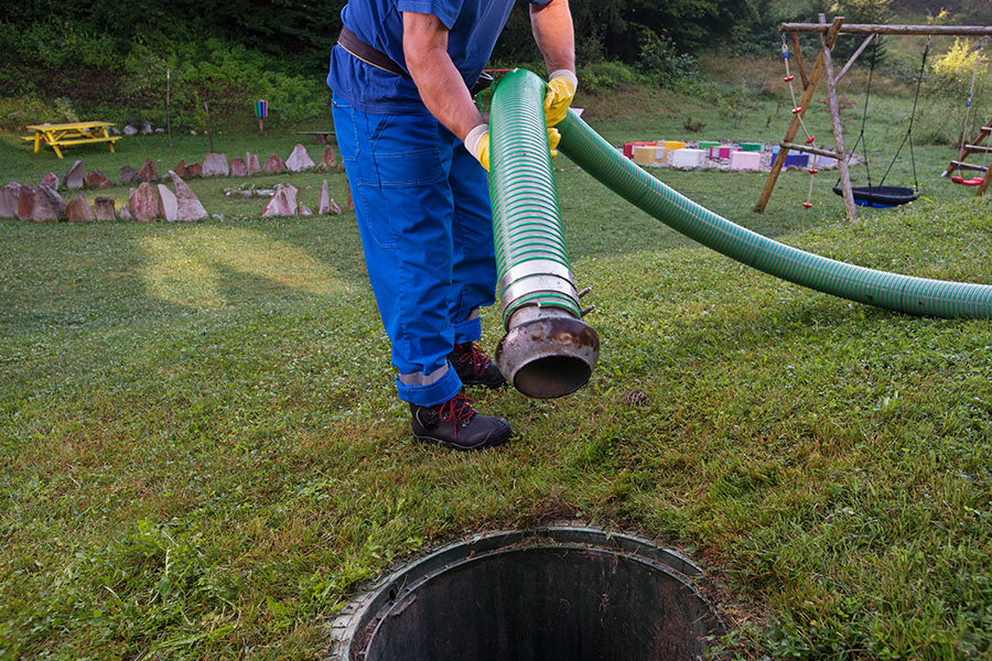 A professional septic tank and sewer pumping technician cleaning a septic system in Decatur, IL.