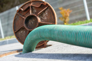 A green hose pumping a sewer system for a general sewage cleaning service at a residential home in Decatur, IL.