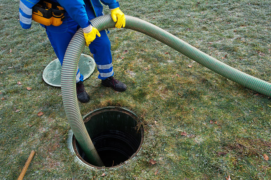 A professional plumbing technician is emptying a Lincoln, IL household’s septic tank and cleaning sludge from the system.
