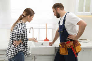 A homeowner consults with a professional plumbing technician to address her clogged kitchen sink in Lincoln, IL.