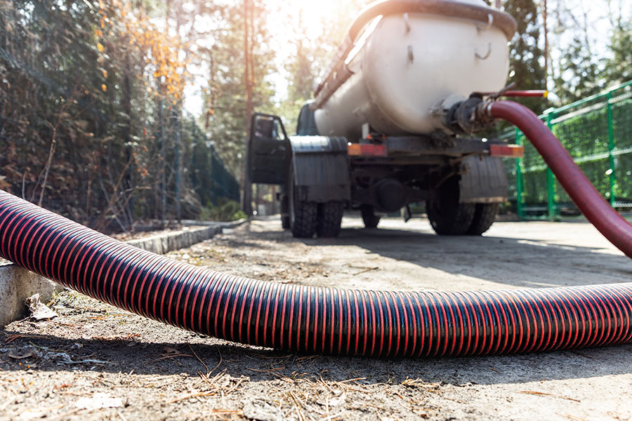 The pipe hose of a sewage truck is pumping and emptying the home’s sewage tank. Professionals provide a septic cleaning vacuum service and maintenance for this suburban countryside home in Bloomington, IL.