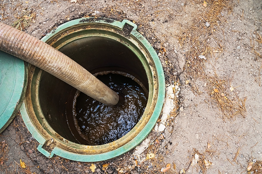 Sewer & Septic Specialist – Maintenance work - A septic system is being pumped out with a pipe in the drainage pit at a property in Decatur, IL.