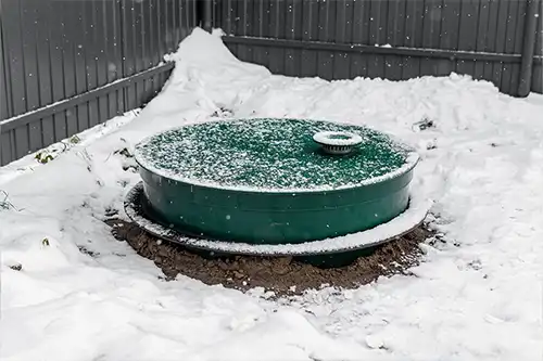 Sewer & Septic Specialists—A green septic tank on a property in Decatur, IL, surrounded by winter snow.