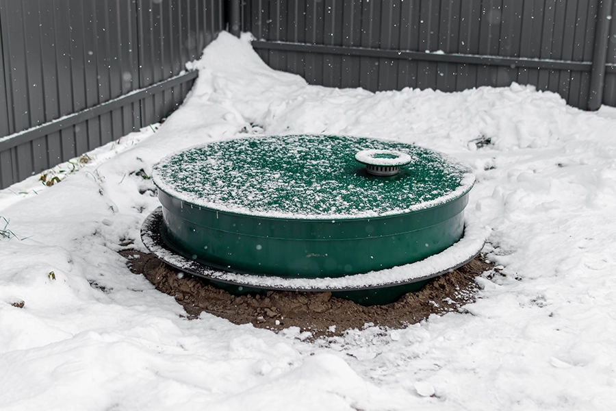 Sewer & Septic Specialists—A green septic tank on a property in Decatur, IL, surrounded by winter snow.